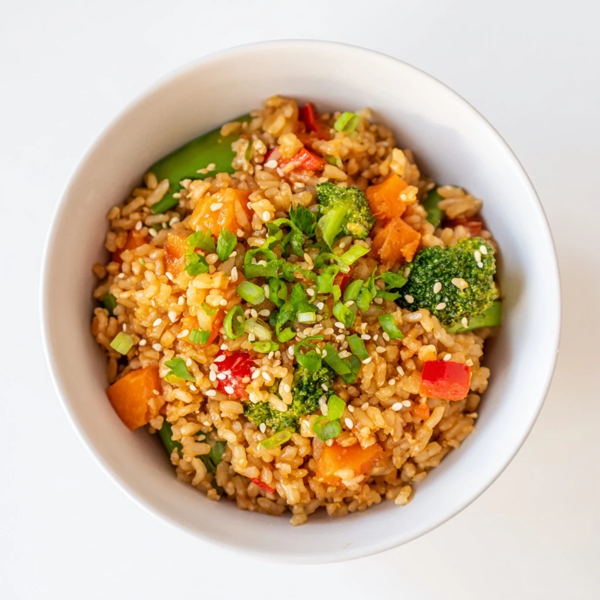 A steaming bowl of Crispy Vegetable Fried Rice showcases perfectly cooked rice and a medley of vibrant stir-fried veggies.