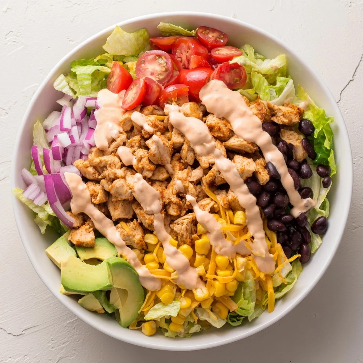 A bowl of vibrant Chicken Taco Chopped Salad with seasoned chicken, crisp lettuce, avocado, and crushed tortilla chips.