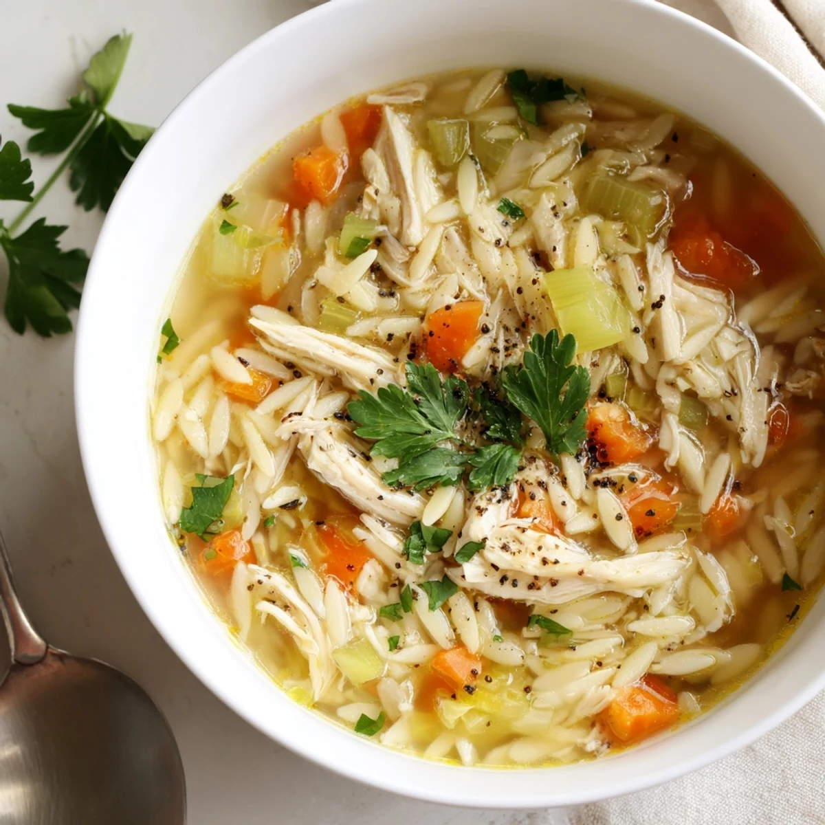 Cozy homemade Lemon Pepper Chicken Orzo Soup in a bowl, featuring zesty lemon and black pepper aromatics, ready to serve.
