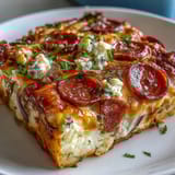 A close-up slice of High-Protein Pizza Breakfast Casserole showing fluffy egg layers, red bell peppers, and rich mozzarella topping.