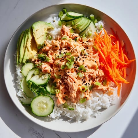 Imagine the flavorful Spicy Canned Salmon Rice Bowl: steamed rice topped with flaky salmon and fresh toppings.
