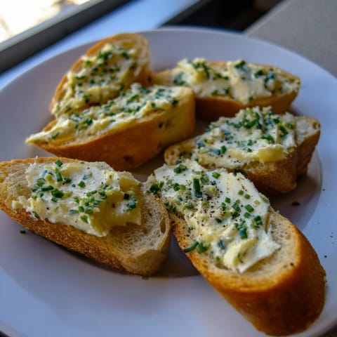 Golden-brown vodka butter crostini topped with fresh chives and lemon zest on a rustic wooden board.