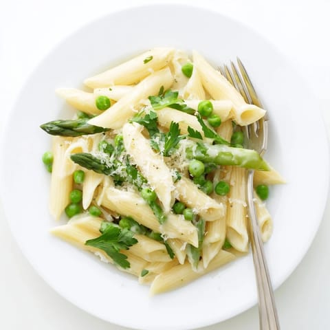 A close-up of Garlic Parmesan Spring Vegetable Pasta, with tender vegetables and glistening sauce under soft kitchen lighting.