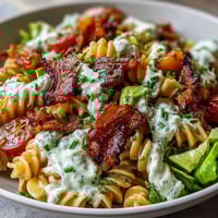 Vibrant BLT pasta with avocado ranch, featuring crispy bacon, fresh tomatoes, and creamy dressing on a bed of pasta.